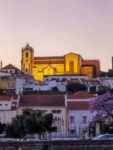 a yellow building with a church in the background at Ponte Romana in Silves