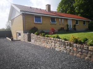 una casa con una valla de piedra delante de ella en Kastanievejens overnatning, en Svendborg