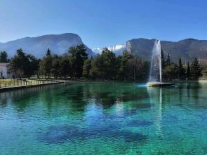 a fountain in a lake with mountains in the background at OLYMPUS HILL in Litochoro