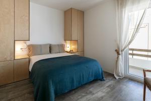 a bedroom with a bed with a blue blanket and a window at Mare Cheia: Beach and Surf Apartment 2 in Consolação
