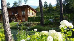 eine Hütte im Wald mit einem Teich und Blumen in der Unterkunft Ferienwohnung Bettina in Berg im Drautal