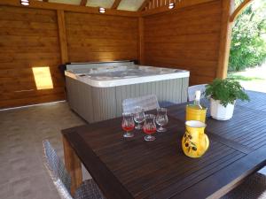 a wooden table with wine glasses and a hot tub at Melody Huis in Poroszló