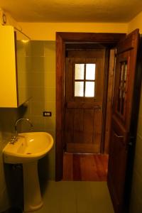 ein Bad mit einem Waschbecken und eine Tür mit einem Fenster in der Unterkunft Nido delle aquile in Cogne