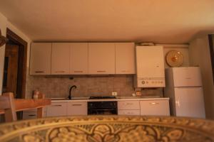 a kitchen with white cabinets and a stove and refrigerator at Nido delle aquile in Cogne