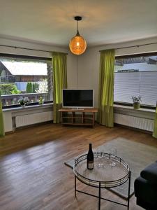 sala de estar con TV y mesa de cristal en Gästehaus Kayetan, en Klais