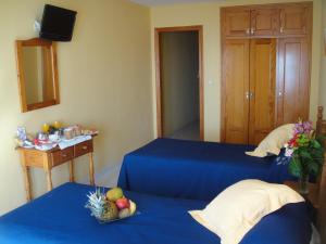 2 łóżka w pokoju z niebieską pościelą i owocami w obiekcie HOSTAL COSTA SOL w mieście Castell de Ferro