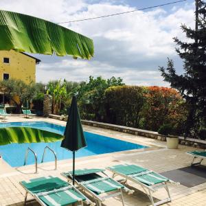 een zwembad met stoelen en een parasol bij Agriturismo Corte Bozzini in Bardolino