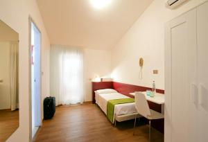 a small room with a bed and a table and a room at Villa Delfa in Caorle