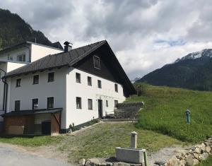 耶爾岑斯的住宿－Landhaus Pitztal inklusive Sommercard，山坡上白色的房子,屋顶黑色