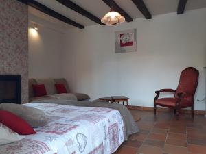 een slaapkamer met een bed en stoelen in een kamer bij Le Petit Brétigny in Beaumont