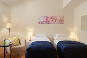 2 Betten in einem Zimmer mit Sofa und Gemälde in der Unterkunft Residence Vocelova in Prag