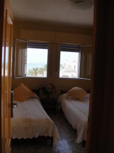 dwa łóżka w pokoju z dwoma oknami w obiekcie HOSTAL COSTA SOL w mieście Castell de Ferro