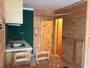 cocina con paredes verdes, fregadero y sillas en House Cervinia Apartments, en Breuil-Cervinia