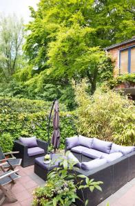 un patio con 2 sofás y una sombrilla en Cottage Markdal, en Breda