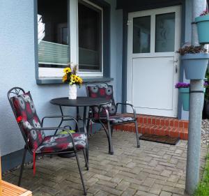 eine Terrasse mit einem Tisch, 2 Stühlen und einer Tür in der Unterkunft Wohlfühl-Apartments in Zingst in Zingst