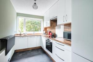 a kitchen with white cabinets and a window at City Centre Stylish Apartment With Free Parking in Edinburgh