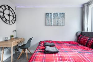 a bedroom with a bed and a desk and a clock at City Centre Stylish Apartment With Free Parking in Edinburgh