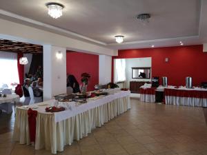 une salle de banquet avec des tables blanches et des murs rouges dans l'établissement Ośrodek Natura, à Pokrzywna