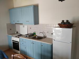 uma cozinha com armários azuis, um lavatório e um frigorífico em Villa Ioanna em Kionia