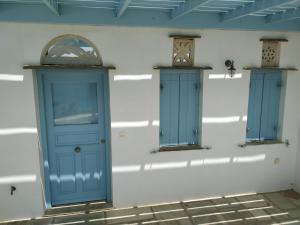 a wall with two blue doors and two windows at Villa Ioanna Tinos in Kionia