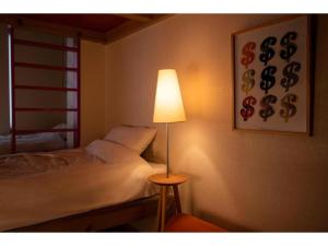 a bedroom with a bed and a lamp next to it at BEYOND HOTEL Takayama 2nd - Vacation STAY 82239 in Takayama