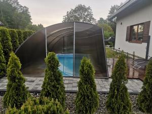 a glass house with a swimming pool in a garden at Domek letniskowy z basenem in Kołczewo