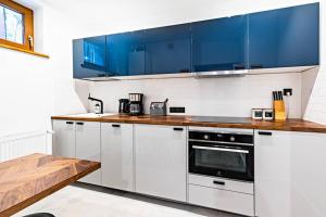 kuchnia z białymi blatami i niebieskimi szafkami w obiekcie Blick Apartments - Riverview Soft Loft w mieście Zgorzelec