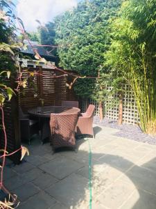a patio with a table and chairs and trees at The Lodge at The Cedars in Stourbridge