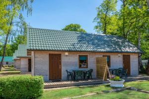 un piccolo cottage bianco con tavolo e sedie di O.W.Cynamon a Dziwnów