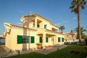 a white house with green shutters and a palm tree at Altura Prime - 5 Suites, Private Pool and Parking, Walk to Beach in Altura +33 photos