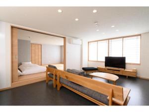 a room with a bench and a bed and a television at BEYOND HOTEL Takayama 3rd - Vacation STAY 82217 in Takayama