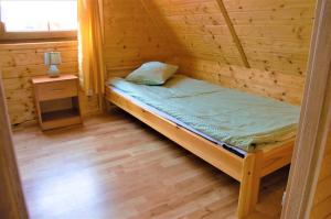 a small bedroom with a bed in a log cabin at Domki Letniskowe Orka in Jarosławiec +20 photos