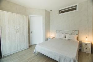 a bedroom with a white bed and a white cabinet at New Wave 1 in Batumi