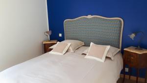 a bedroom with a large white bed with a blue wall at gîte de bon air in Sens-de-Bretagne