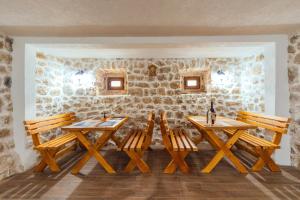 3 mesas y sillas de madera en una habitación con una pared de piedra en Apartments EcoNature, en Virpazar