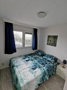 een slaapkamer met een bed en 2 ramen bij Wuivend Riet gelegen op Resort Venetie in Giethoorn