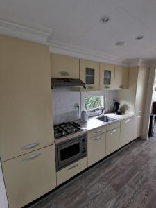 uma cozinha com armários brancos e um forno com placa de fogão em Wuivend Riet gelegen op Resort Venetie em Giethoorn