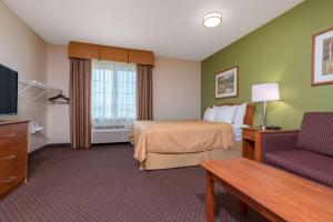 a hotel room with a bed and a couch at Days Inn & Suites by Wyndham Rochester South in Rochester