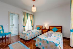 a bedroom with two beds and a blue chair at Altura Prime - 5 Suites, Private Pool and Parking, Walk to Beach in Altura