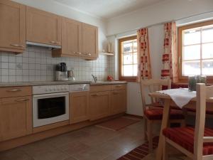 a kitchen with wooden cabinets and a table and a table and chairs at Ferienwohnung Innerlipper in Innervillgraten