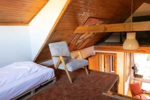 sypialnia z łóżkiem i krzesłem w pokoju w obiekcie Domek Malarza Matarnia w Gdańsku