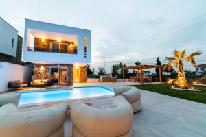 a villa with a swimming pool and two white couches at Achinos Luxury Accomodation- Pefkochori Chalkidiki in Pefkohori