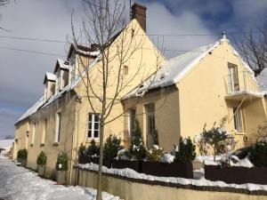a yellow house with snow on the roof at Gîte du banc de scie in Ceton