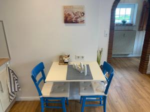 ein Esszimmer mit einem Tisch und blauen Stühlen in der Unterkunft Ferienhaus Anker an der Nordsee in Dornum