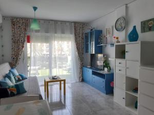 un soggiorno con mobili bianchi e blu e una finestra di Apartamento Tropicana a Denia