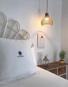 - une chambre avec un lit blanc et une lampe pendant dans l'établissement Casapuerta El Refugio, à Zahara de los Atunes