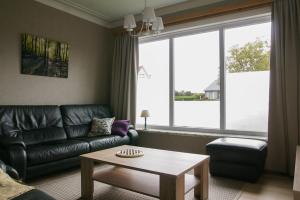 a living room with a leather couch and a coffee table at Vakantiewoning Hoge Zavel in Brakel