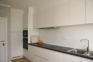 a white kitchen with white cabinets and a sink at Vakantiewoning Hoge Zavel in Brakel