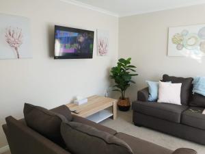 uma sala de estar com um sofá e uma mesa em Rose Apartments Unit 1 Central Rotorua-Accommodation&Spa em Rotorua