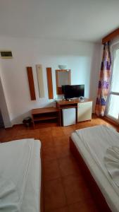 a bedroom with a bed and a desk with a television at Hotel Bon Relax in Ravadinovo